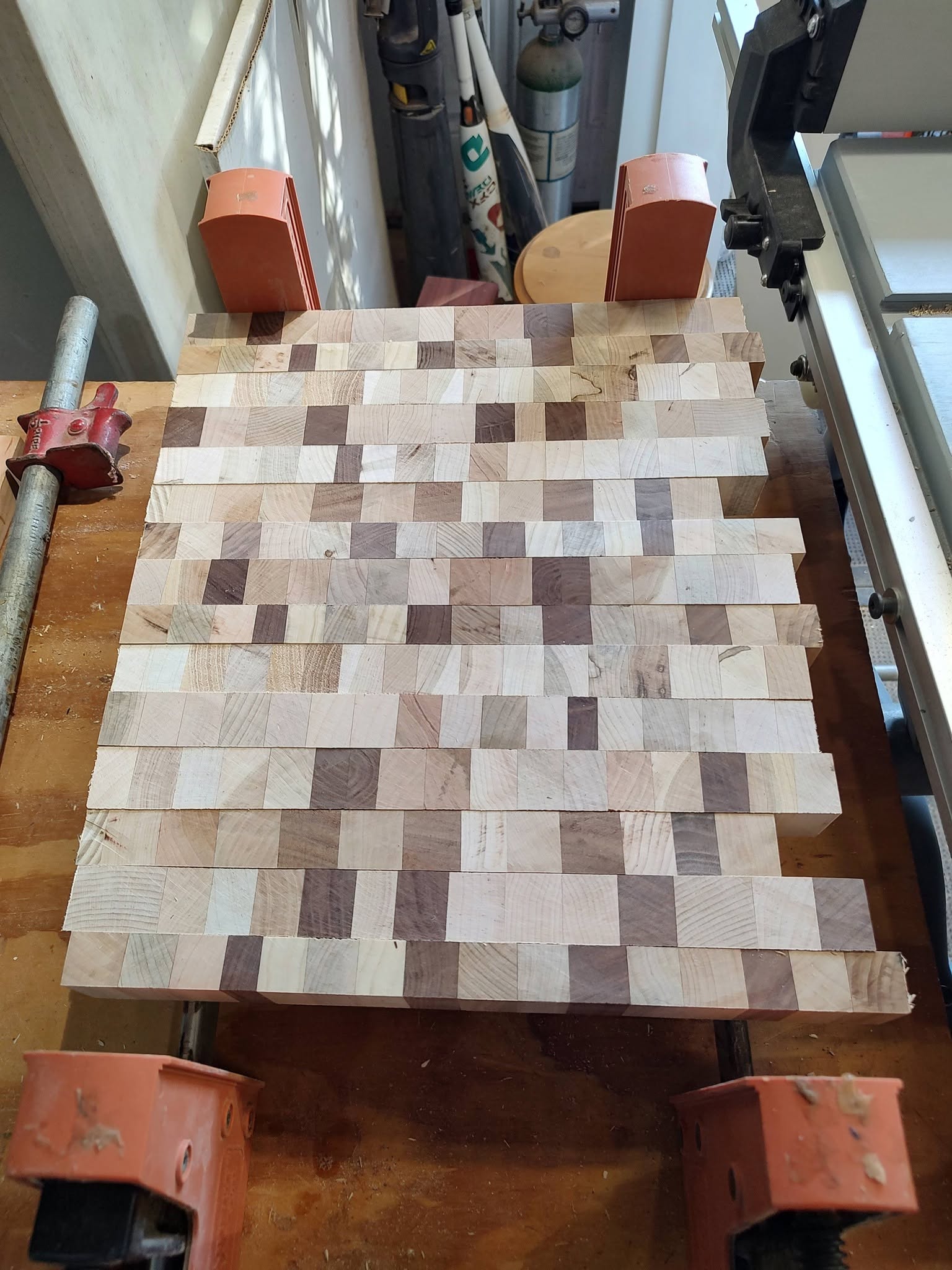 An end-grain board being assembled in clamps on a workshop bench