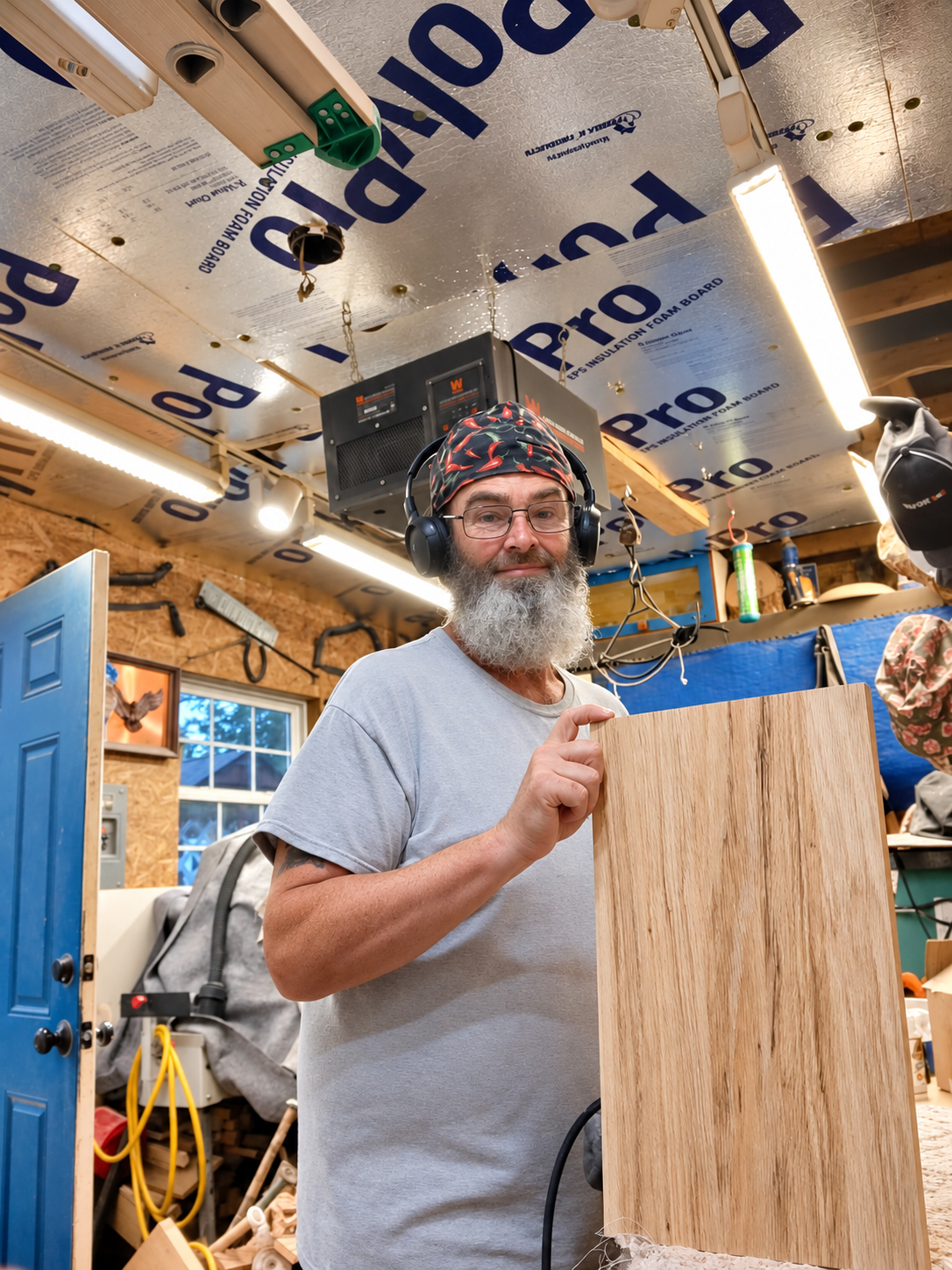 A maker holding a wood board in the woodworking shop